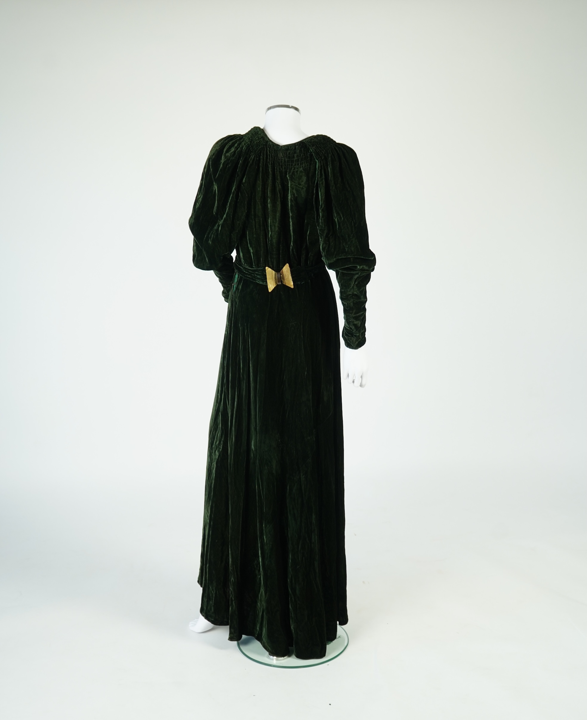 A flesh coloured 1930s lace evening dress and matching jacket together with a bottle green velvet evening dress and buckle belt and an unusual green shot silk pleated under skirt. Lace dress bust 32 inches. 156cm long. C